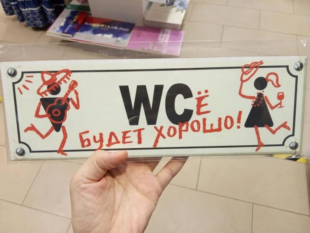 Рука держит табличку с надписью WC будет хорошо и рисунками танцующих человечков