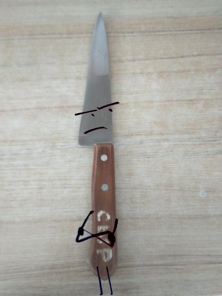 Кухонный нож на разделочной доске, на котором дорисованы расстроенное лицо, руки на поясе и ножки