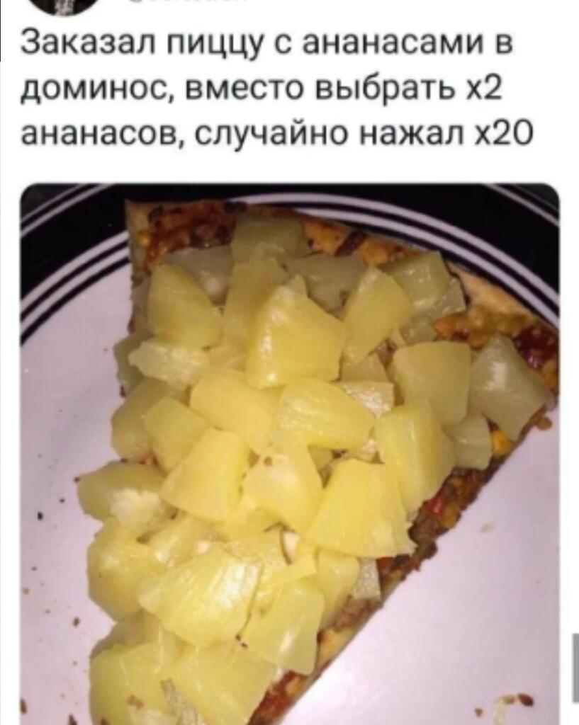 Кусок пиццы, полностью покрытый огромным количеством нарезанных ананасов, на белом тарелке с чёрными полосами