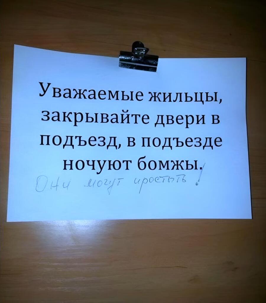 Лист бумаги с напечатанным текстом «Уважаемые жильцы, закрывайте двери в подъезд, в подъезде ночуют бомжи» и припиской от руки «Они могут простыть!