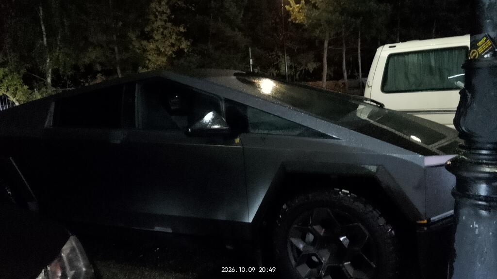 Серебристый Tesla Cybertruck припаркован на улице в ночное время, вид сбоку